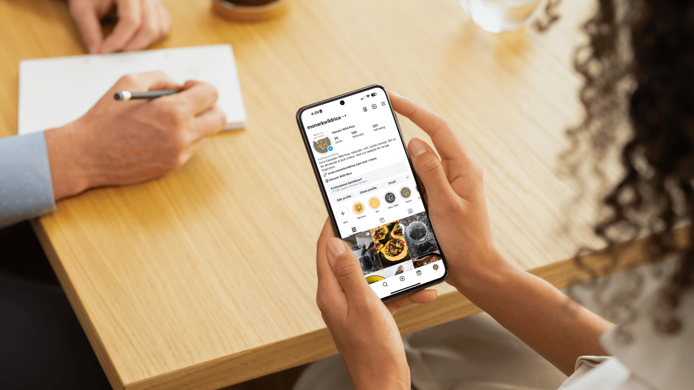Monark Wild Rice Instagram Optimization A person holds a phone showing Monark Wild Rice’s Instagram profile with a branded bio, highlight covers, optimized name field, and contact buttons.
