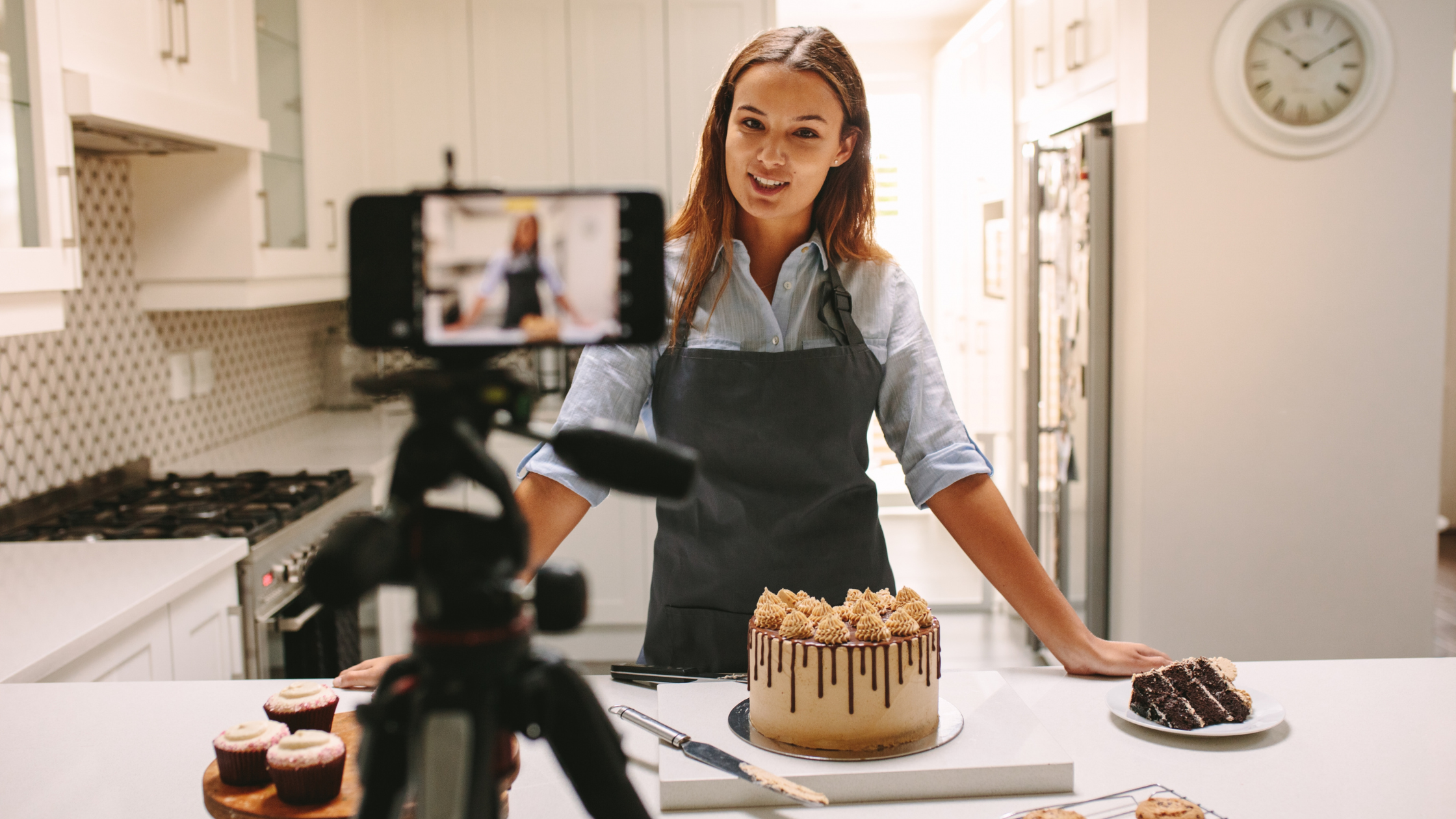 Food Creator Filming Dessert Tutorial for Social Media Female content creator filming cake decorating video in kitchen with professional setup