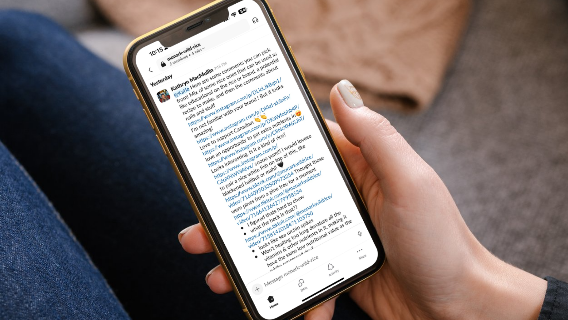 Collaborative Content Strategy in Action A close-up view of a person holding a phone, revealing a group chat where team members share content strategy ideas, Instagram links, and real-time feedback for Monark Wild Rice’s social presence.