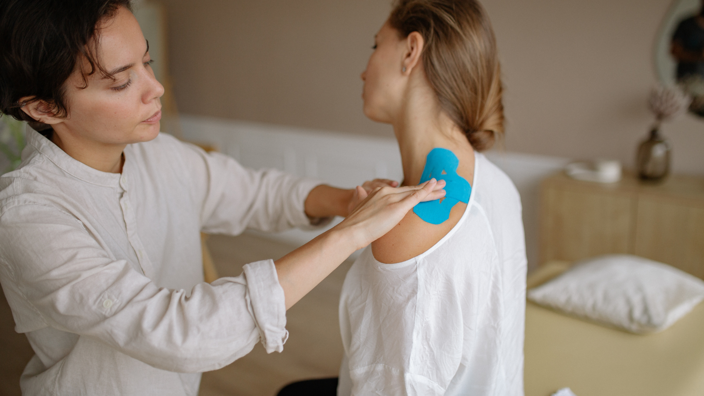 Kinesiology Tape Application for Shoulder Support Healthcare practitioner applying bright blue kinesiology tape to a patient’s shoulder.