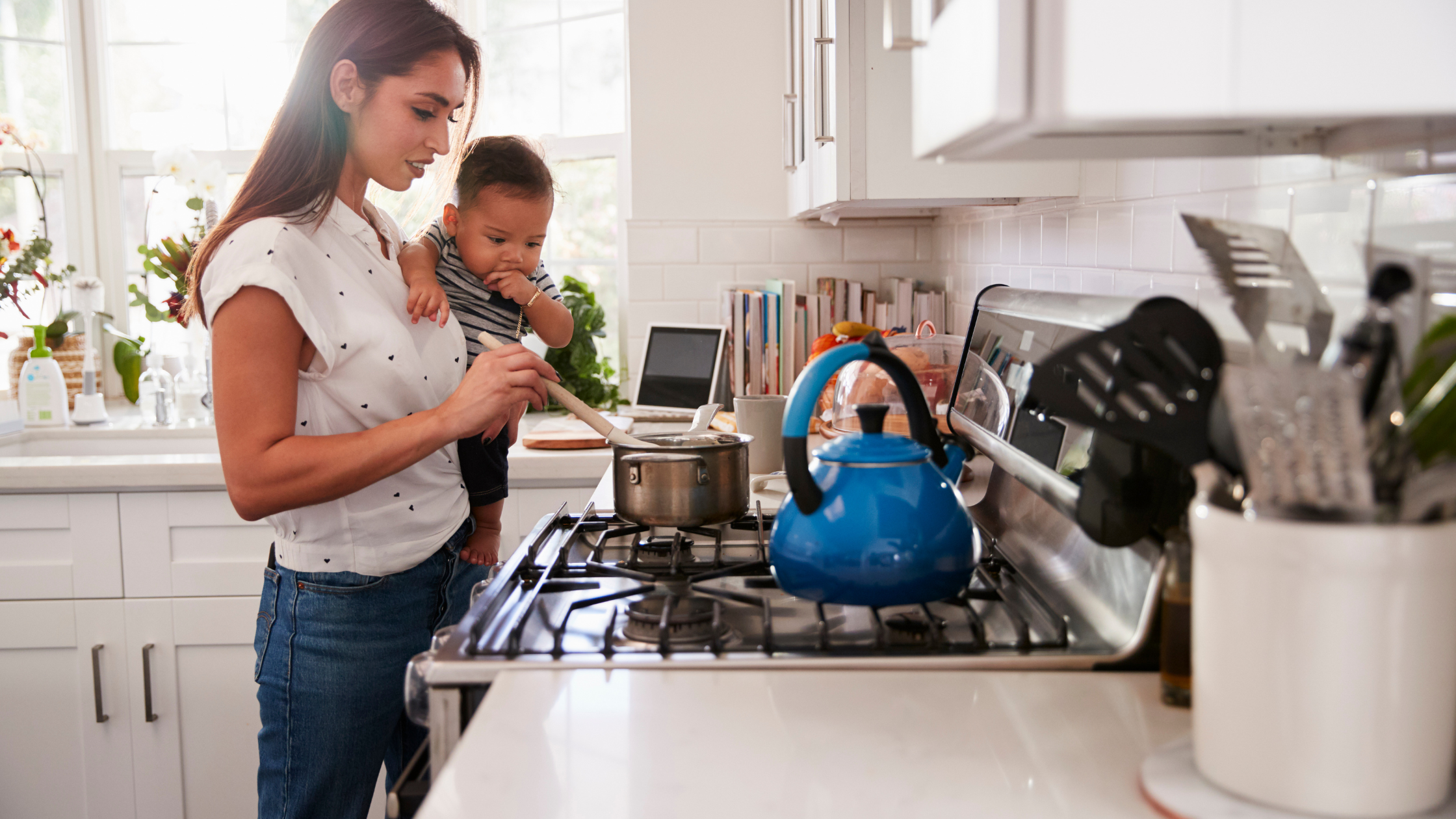Psychographics Over Demographics: Why Context Matters in Persona Building Mother cooking in a bright kitchen while holding a baby, showing real-life context behind a social media persona.