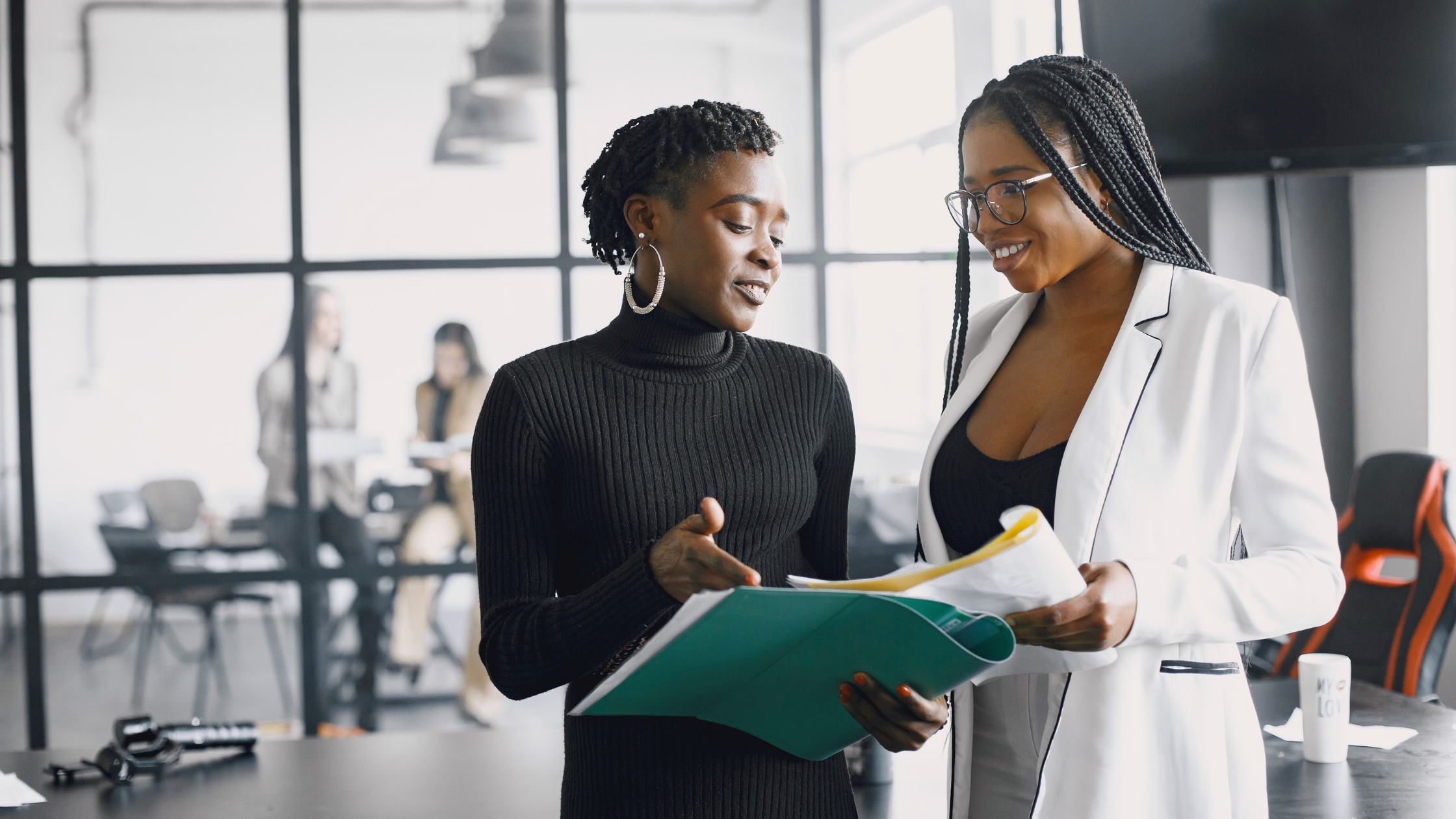 Two Women Collaborating on a Social Media Strategy Two women reviewing documents and discussing ideas in a modern office