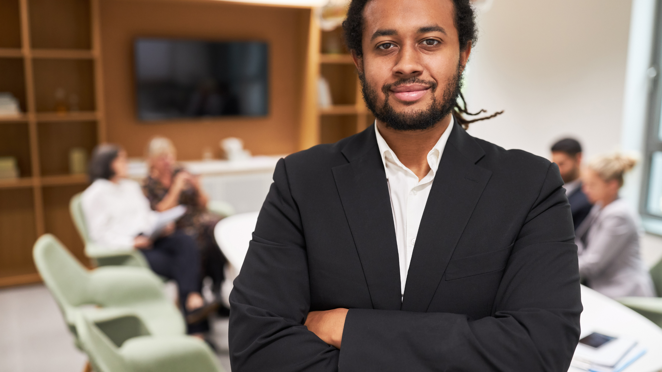 Confident Male Founder in Boardroom Setting Man in a blazer standing confidently in a modern meeting room with colleagues in the background