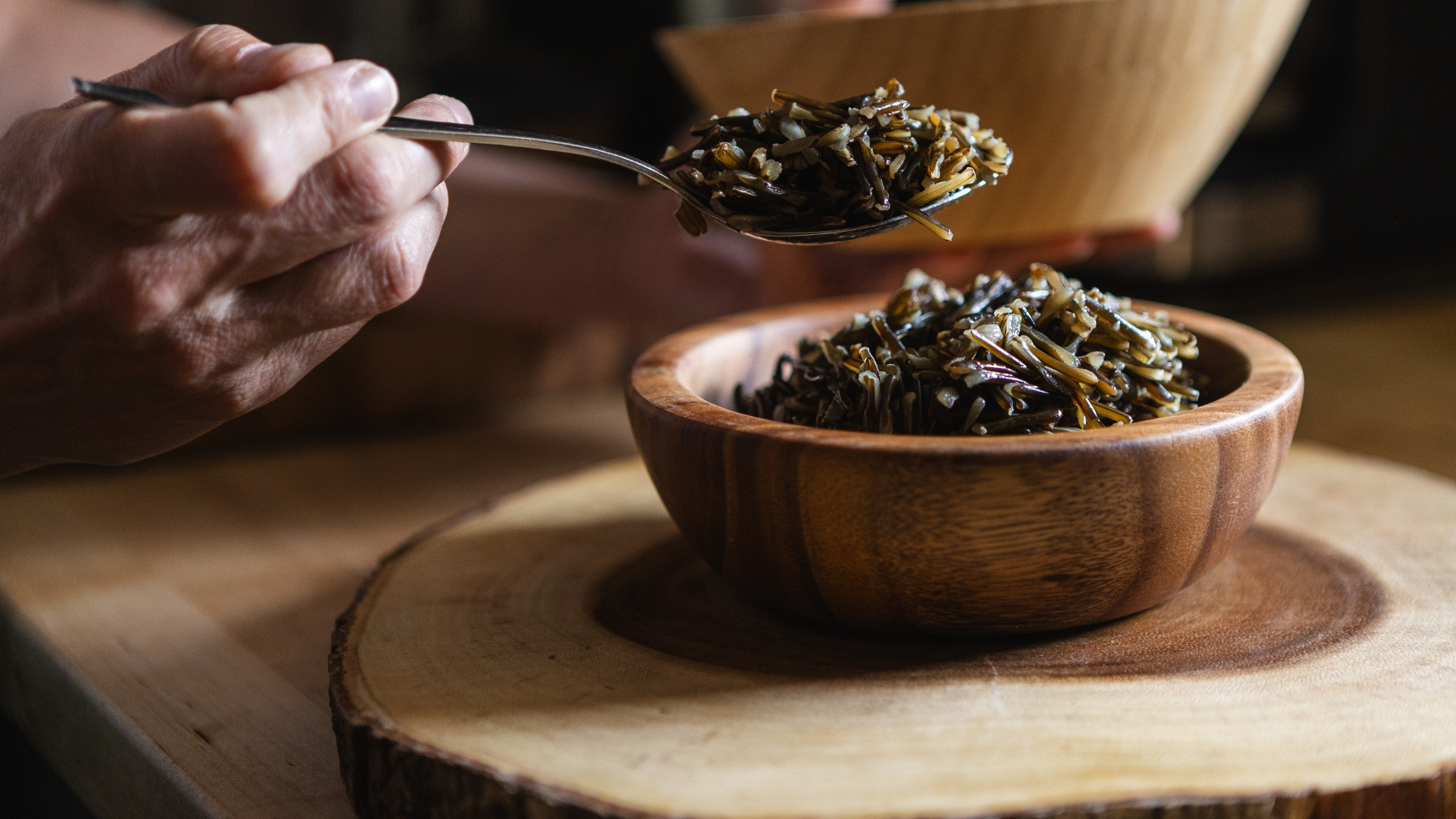 Cooked Wild Rice in Wooden Bowl Close-up of cooked wild rice in a wooden bowl with a spoon.