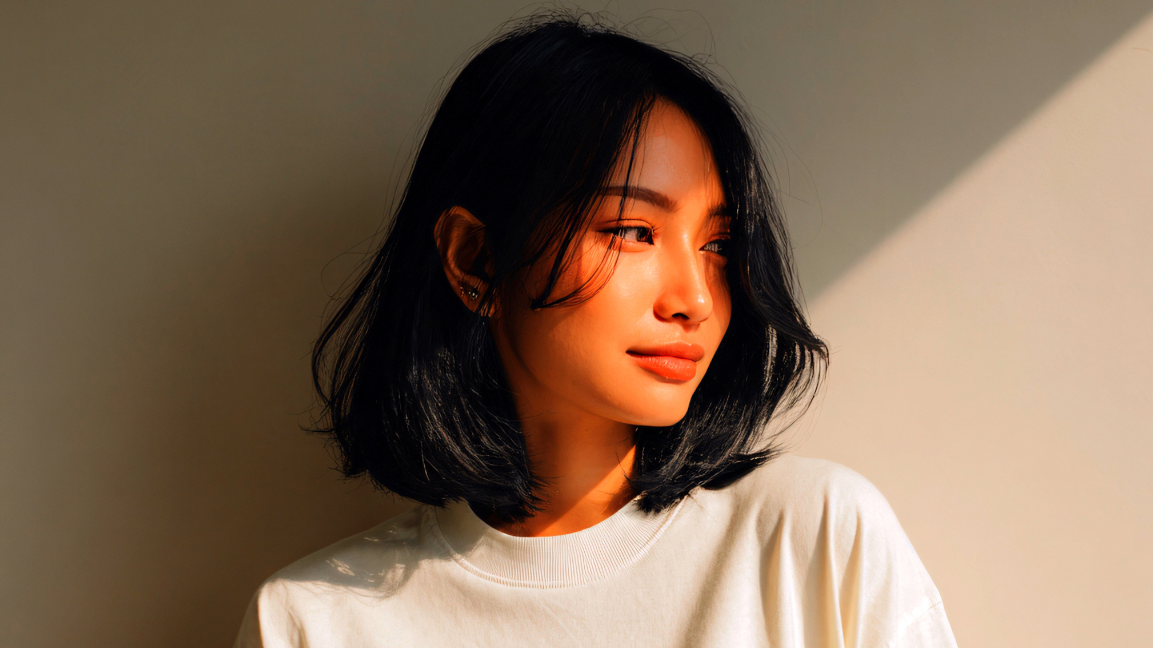 Natural Lighting for Video Creators Woman sitting in natural sunlight by a wall, showing how soft window lighting improves video quality and creates a warm, flattering look.