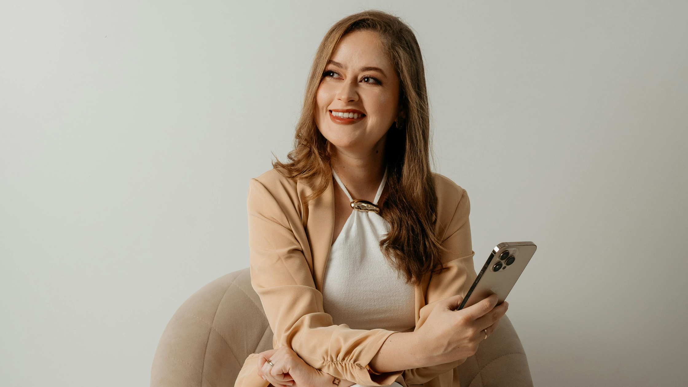 Confident On-Camera Presence Woman smiling while holding a smartphone, representing confidence and strong on-camera presence for creators filming content.