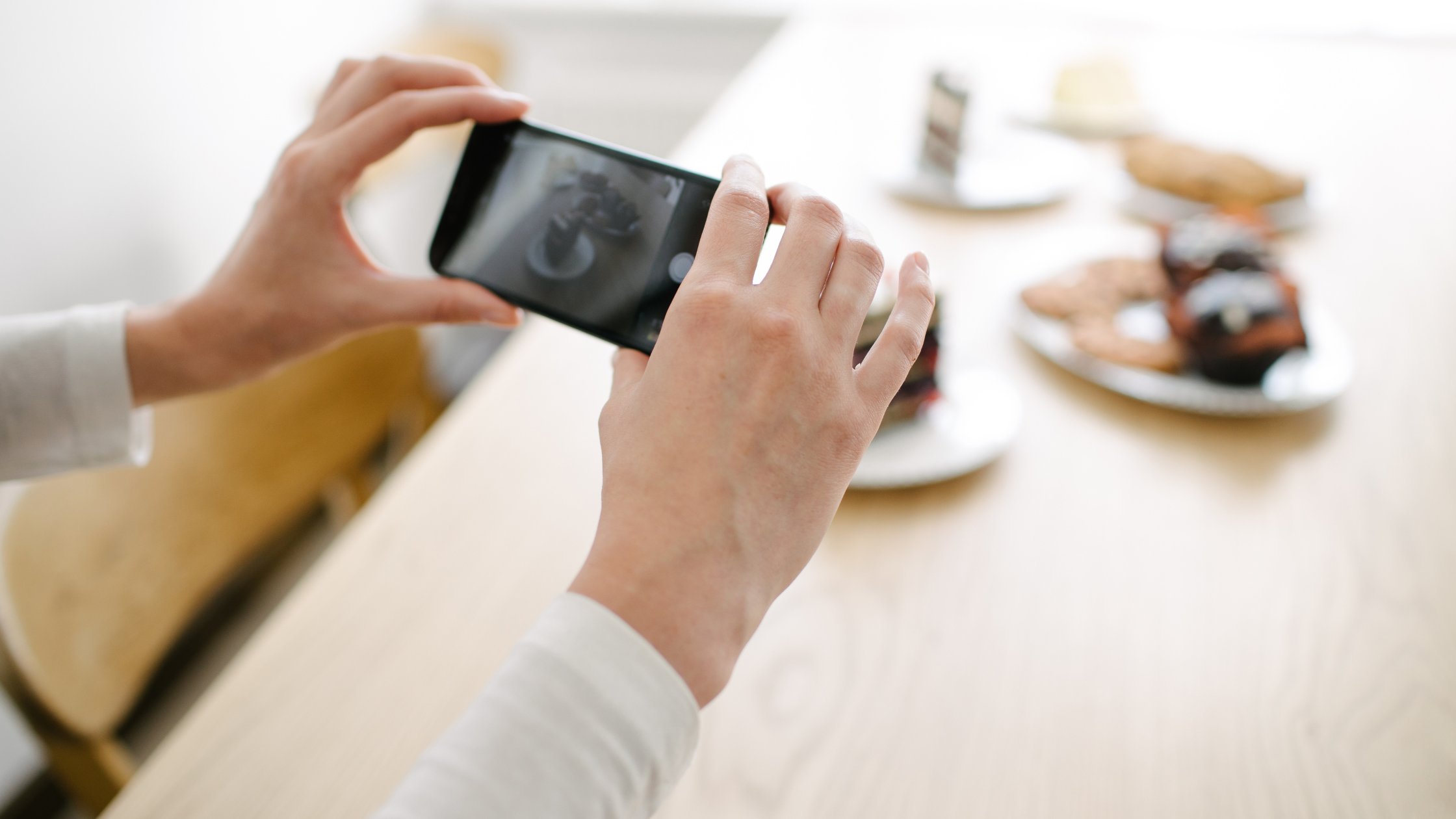 Capturing Content for Social Media Posts Person taking a photo of desserts on a smartphone for social media content creation.