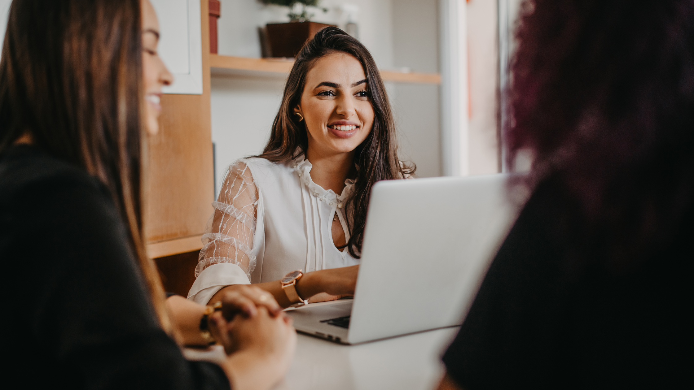 Woman smiling while leading a conversation on her laptop during a collaborative meeting.