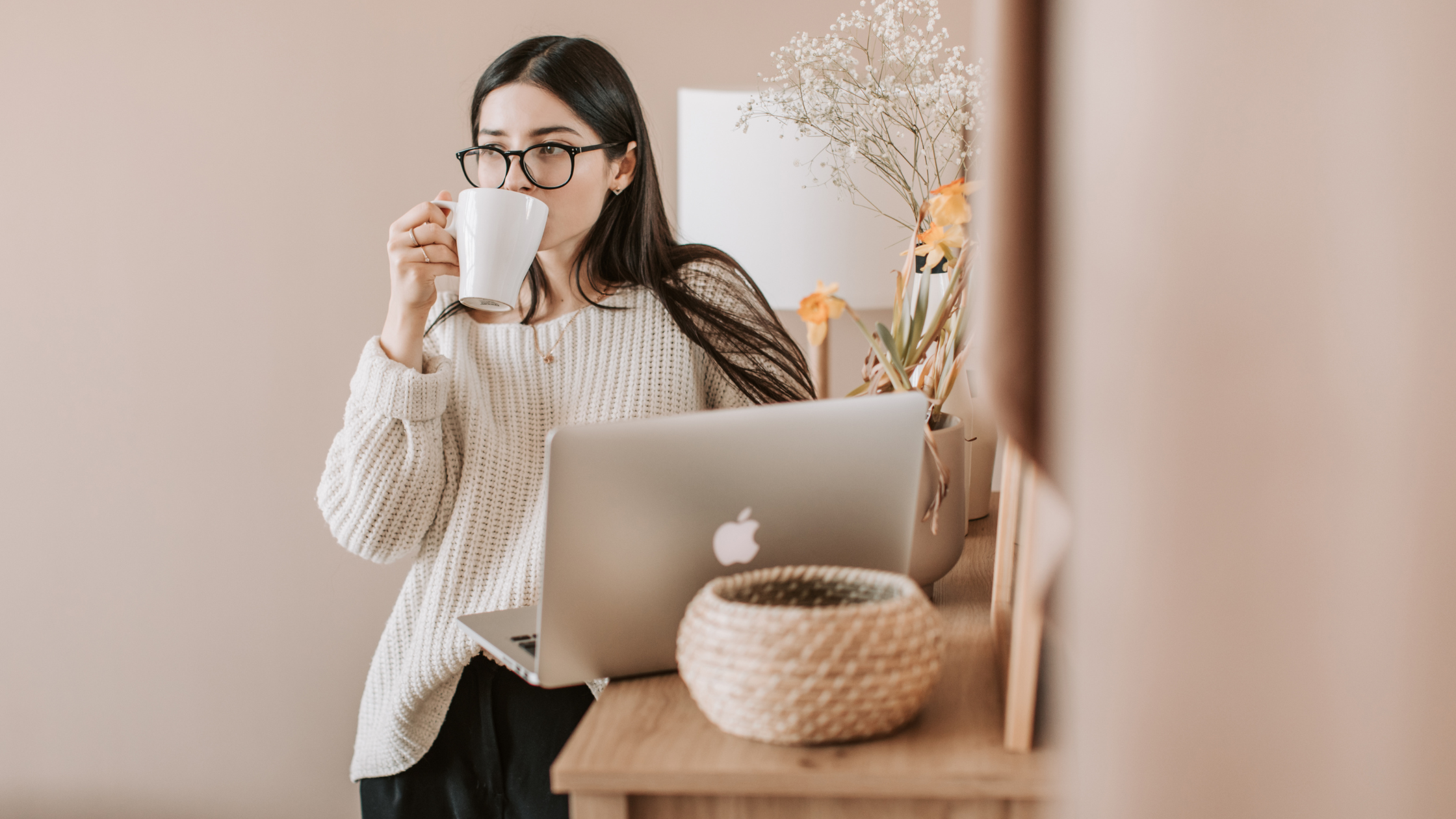 Woman working on a laptop while drinking coffee, representing intentional social media strategy and focused business planning for 2026