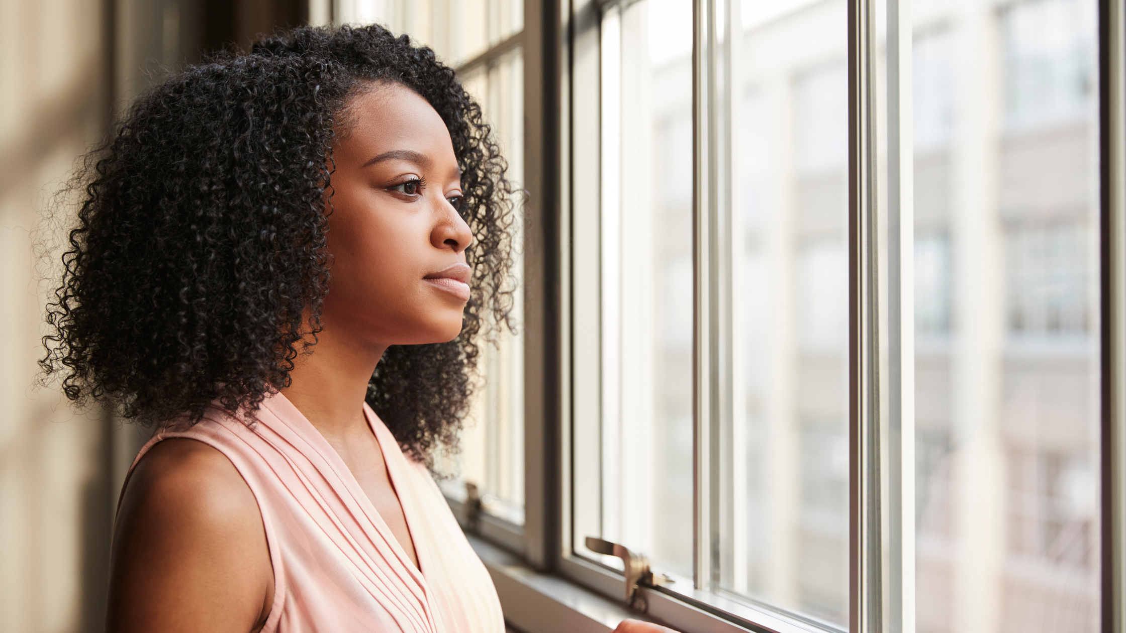 Professional woman looking out a window, symbolizing reflection, long-term strategy and sustainable business growth in 2026