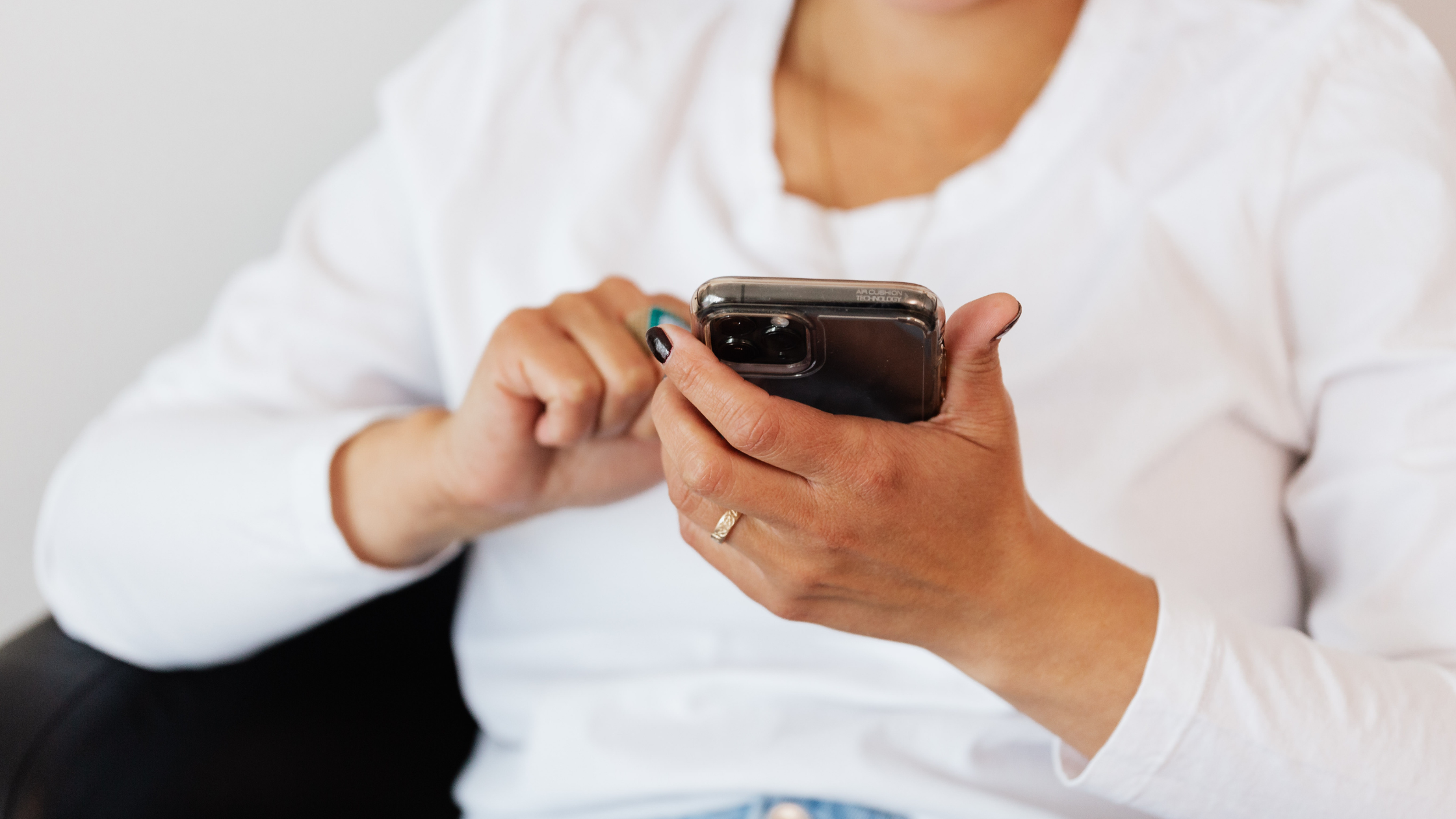 Person using a smartphone while managing social media tasks, representing outsourced social media management