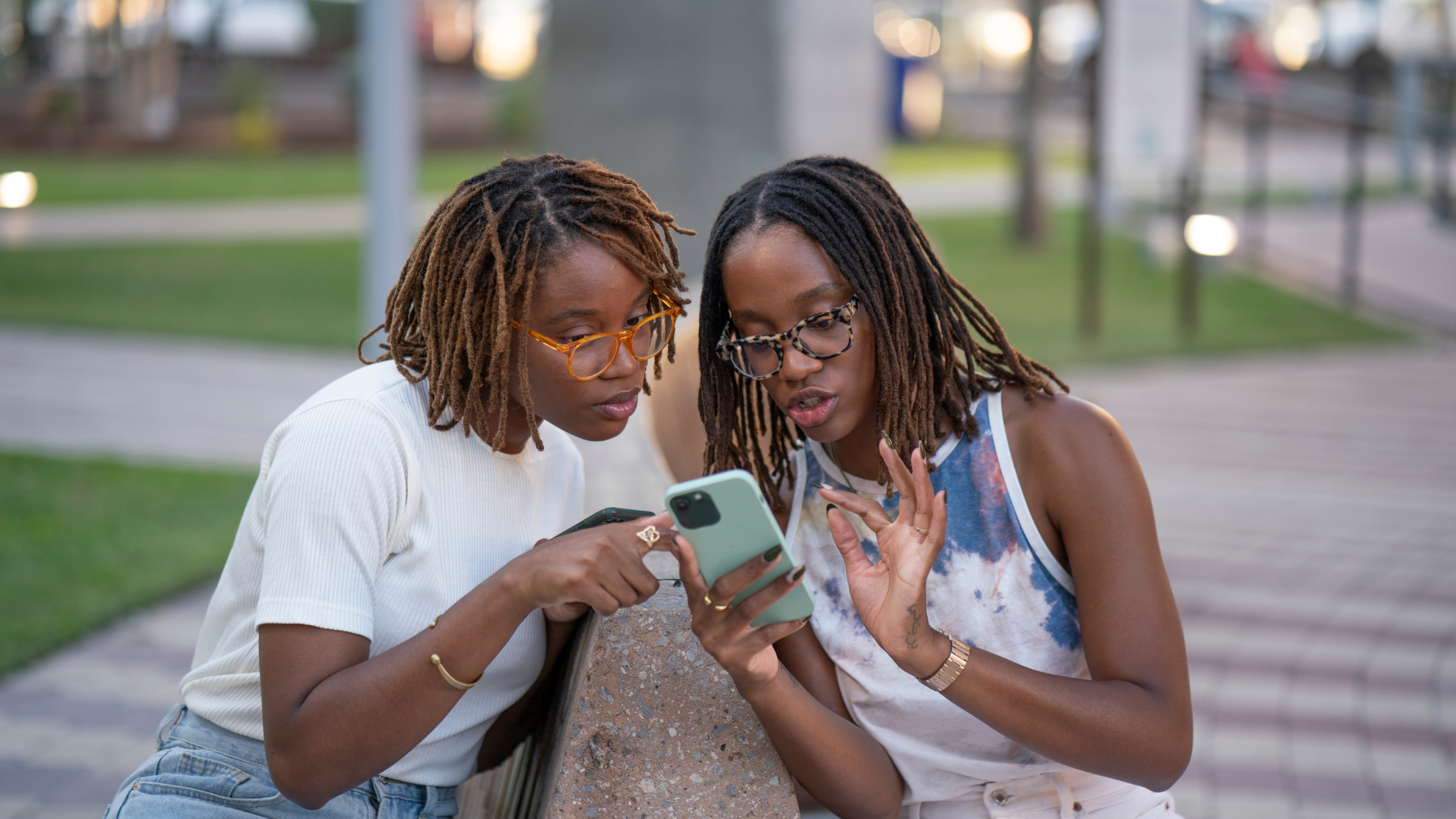 Two professionals reviewing social media content together on a phone, illustrating collaboration in outsourced social media strategy