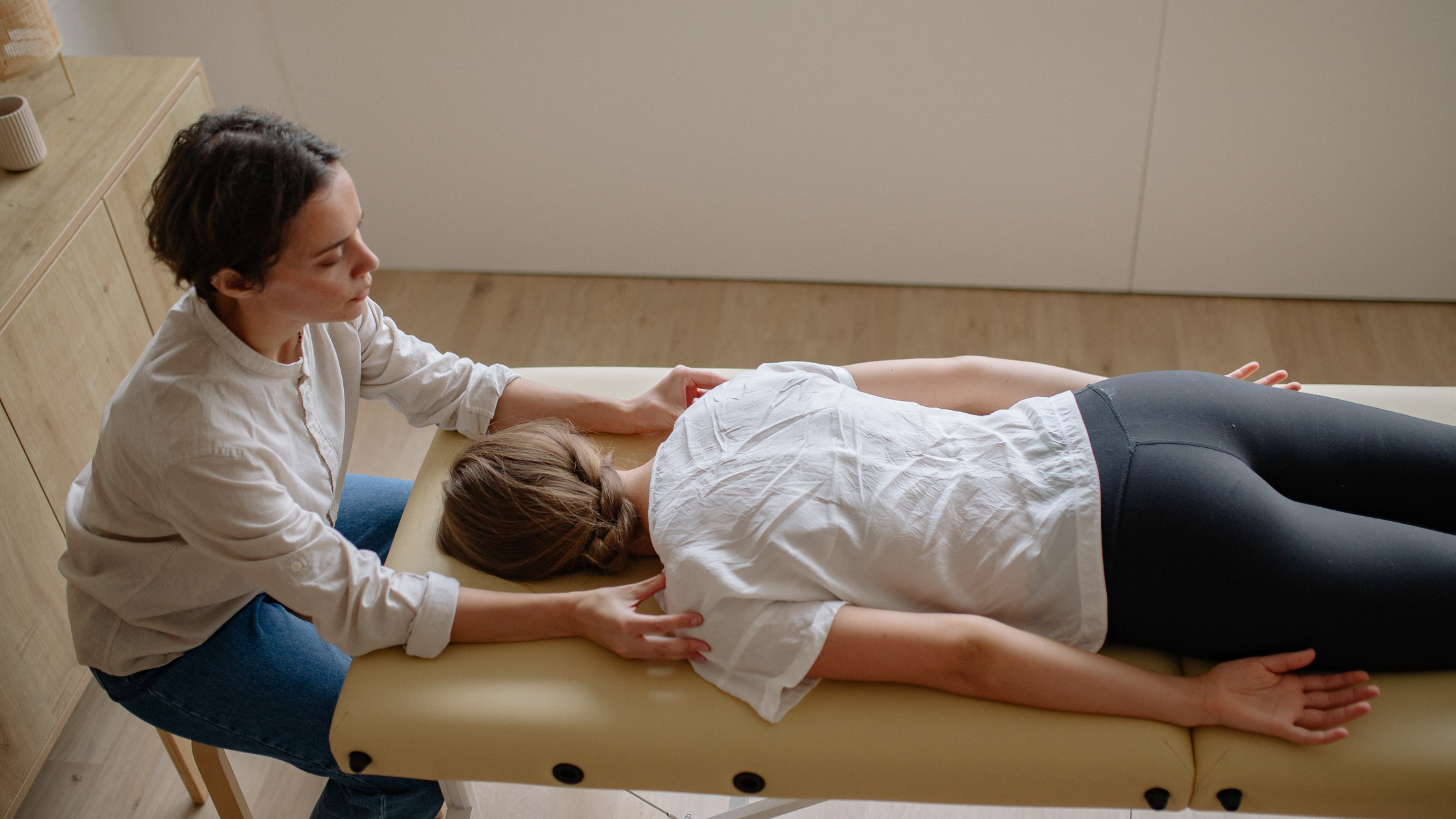 Physiotherapist providing hands-on treatment to a patient lying on a treatment table in a modern clinic