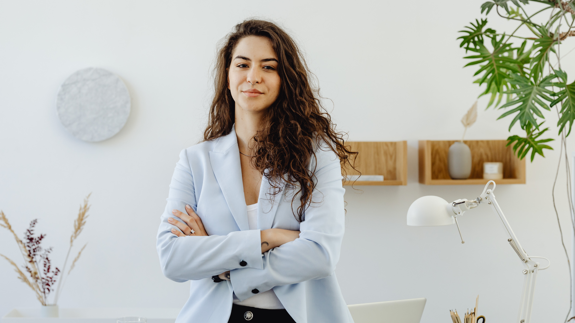 Confident businesswoman with arms crossed in bright, minimalist office