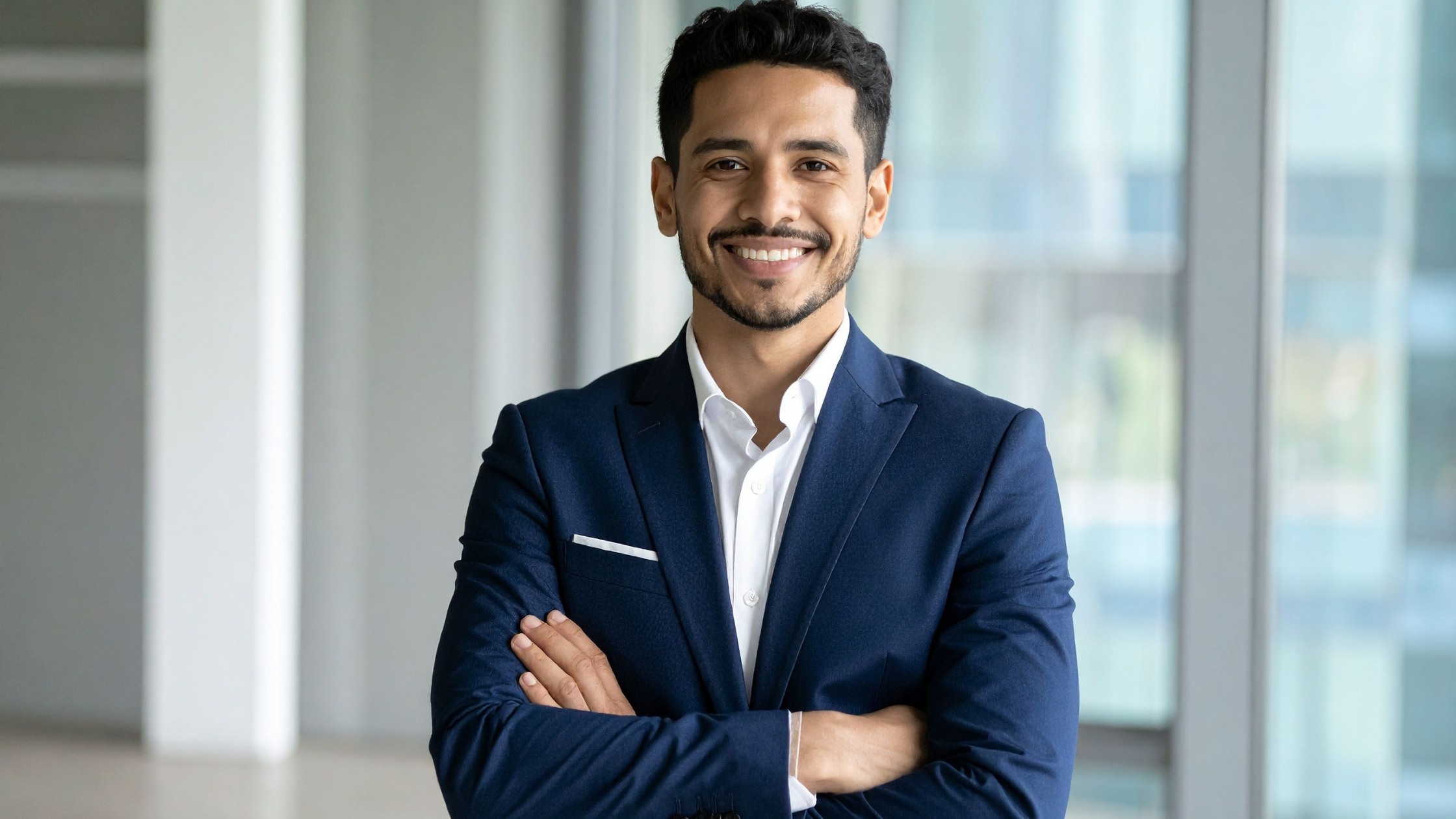Smiling male executive in navy suit standing in corporate office