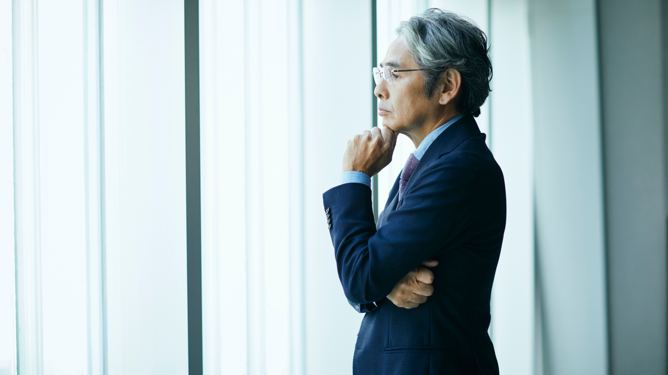 Senior executive thoughtfully looking out office window