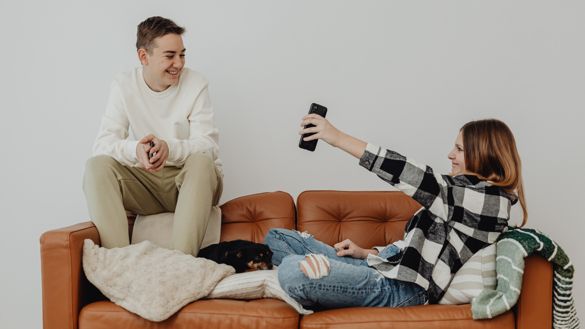 Two friends sitting on a couch taking a selfie with a smartphone for social media