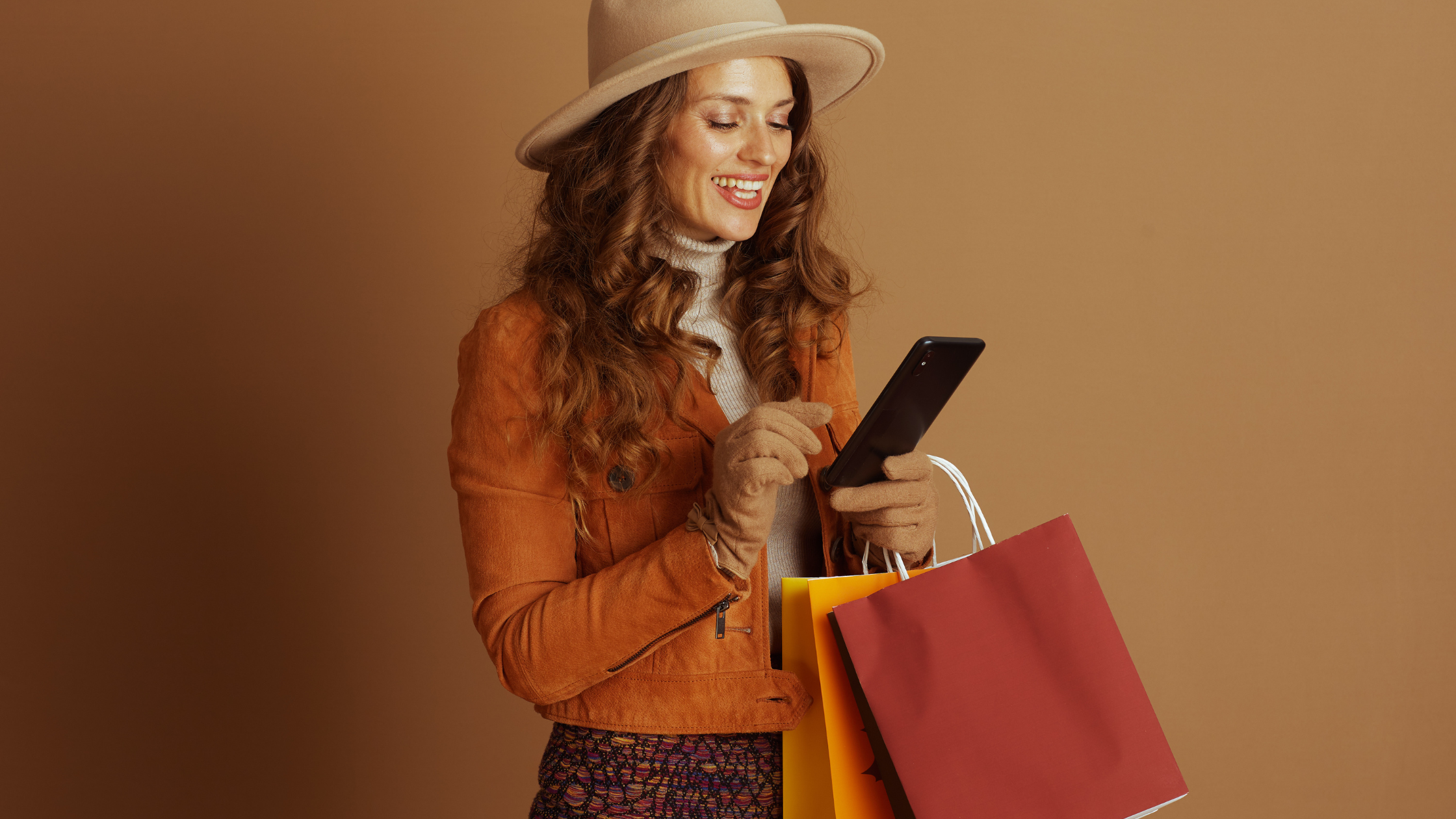 Stylish woman shopping with bags while using smartphone, symbolizing mobile-first brand discovery