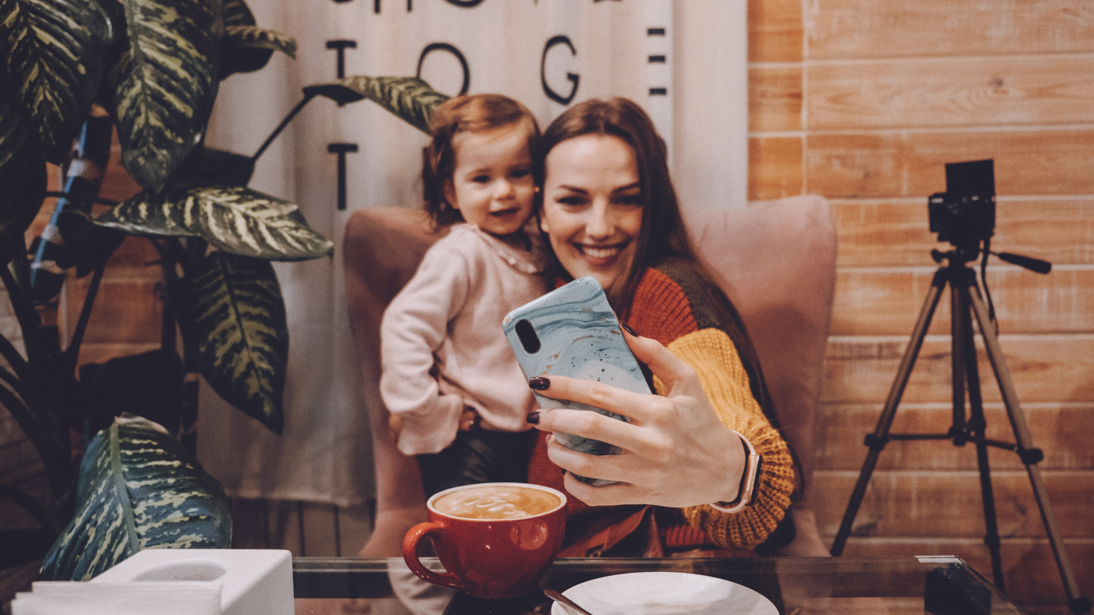 Lifestyle content creator taking a selfie with her child while filming authentic social media content at home.
