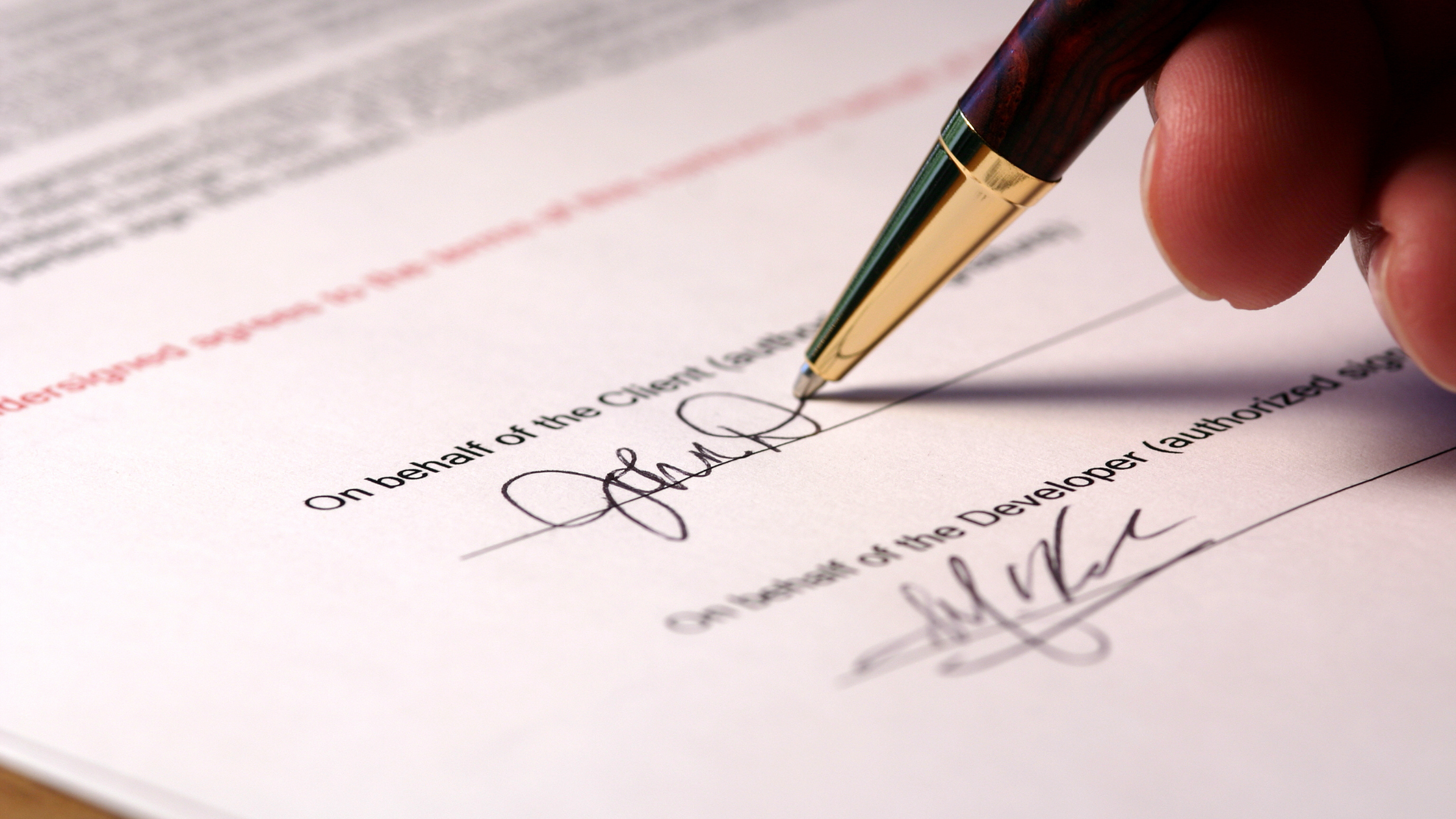Close up of a hand signing a creator partnership contract