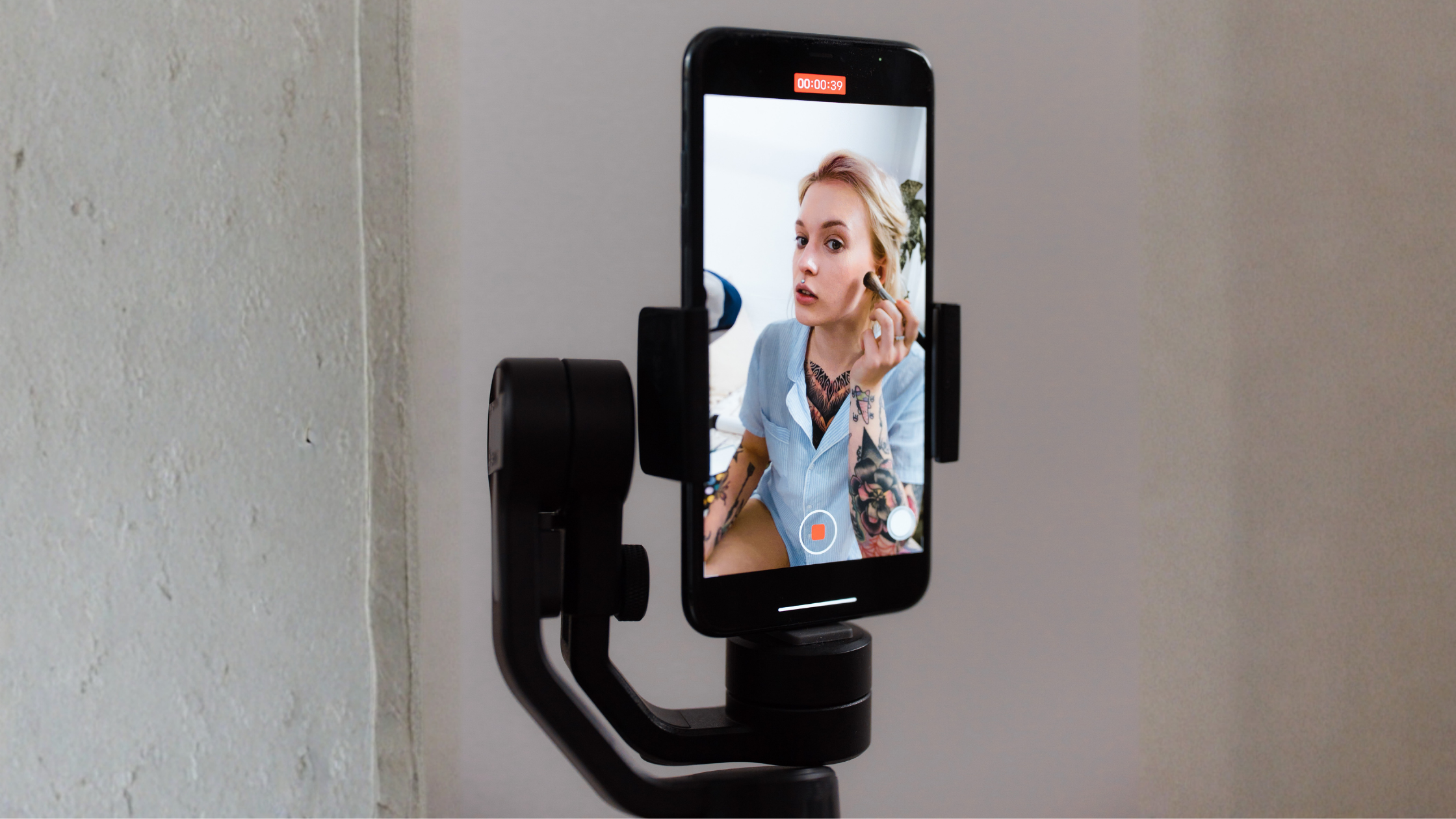 Content creator filming a makeup tutorial on a smartphone mounted to a gimbal