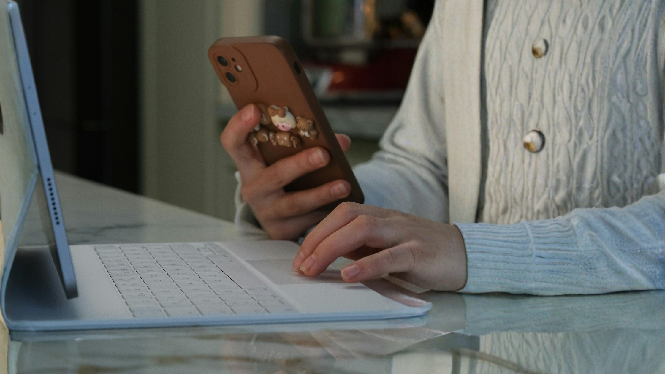 Creator checking phone notifications while working on a laptop, managing brand partnership communication