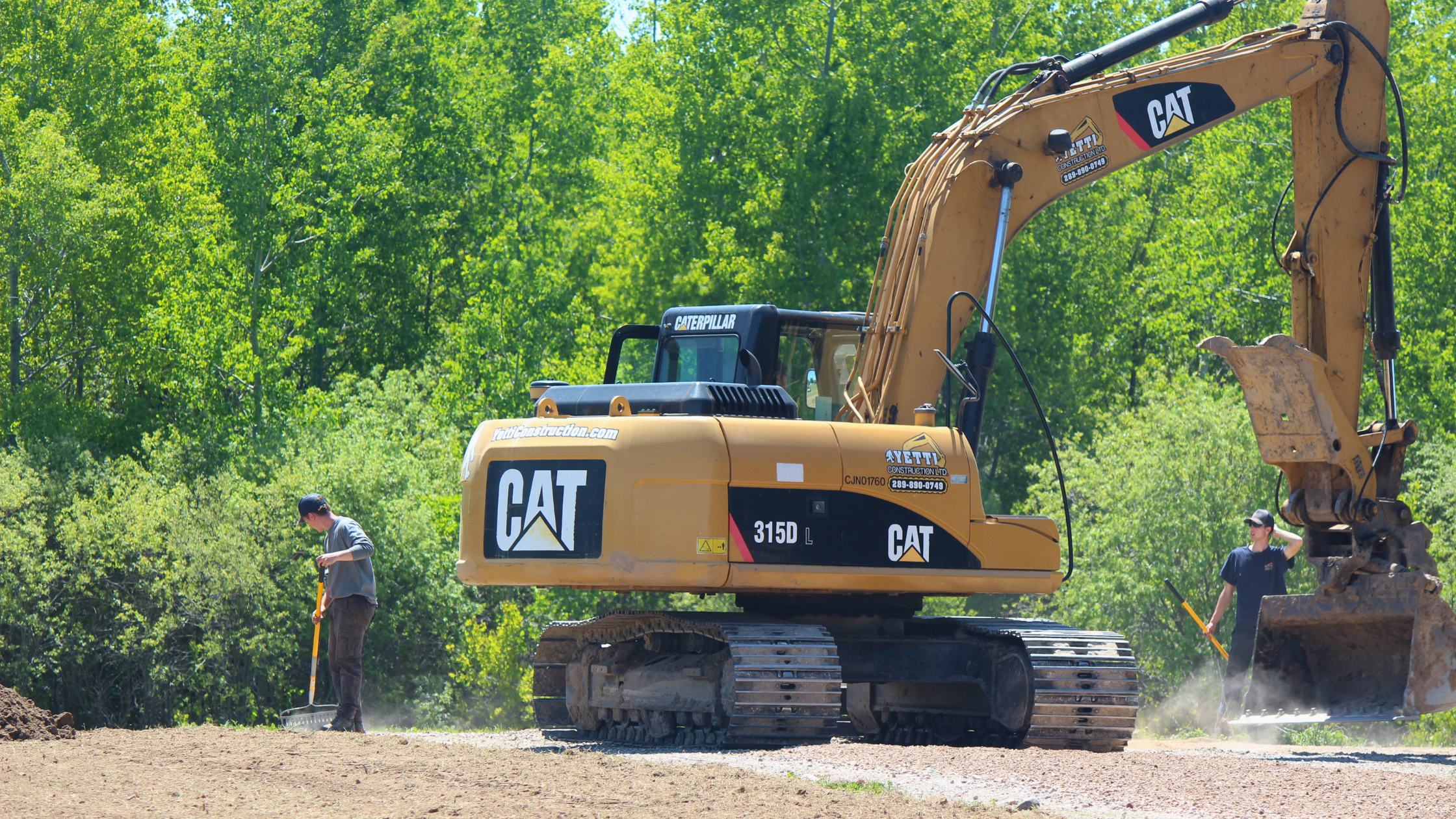CAT 315D L excavator and crew grading a gravel driveway on a Yetti Construction job site