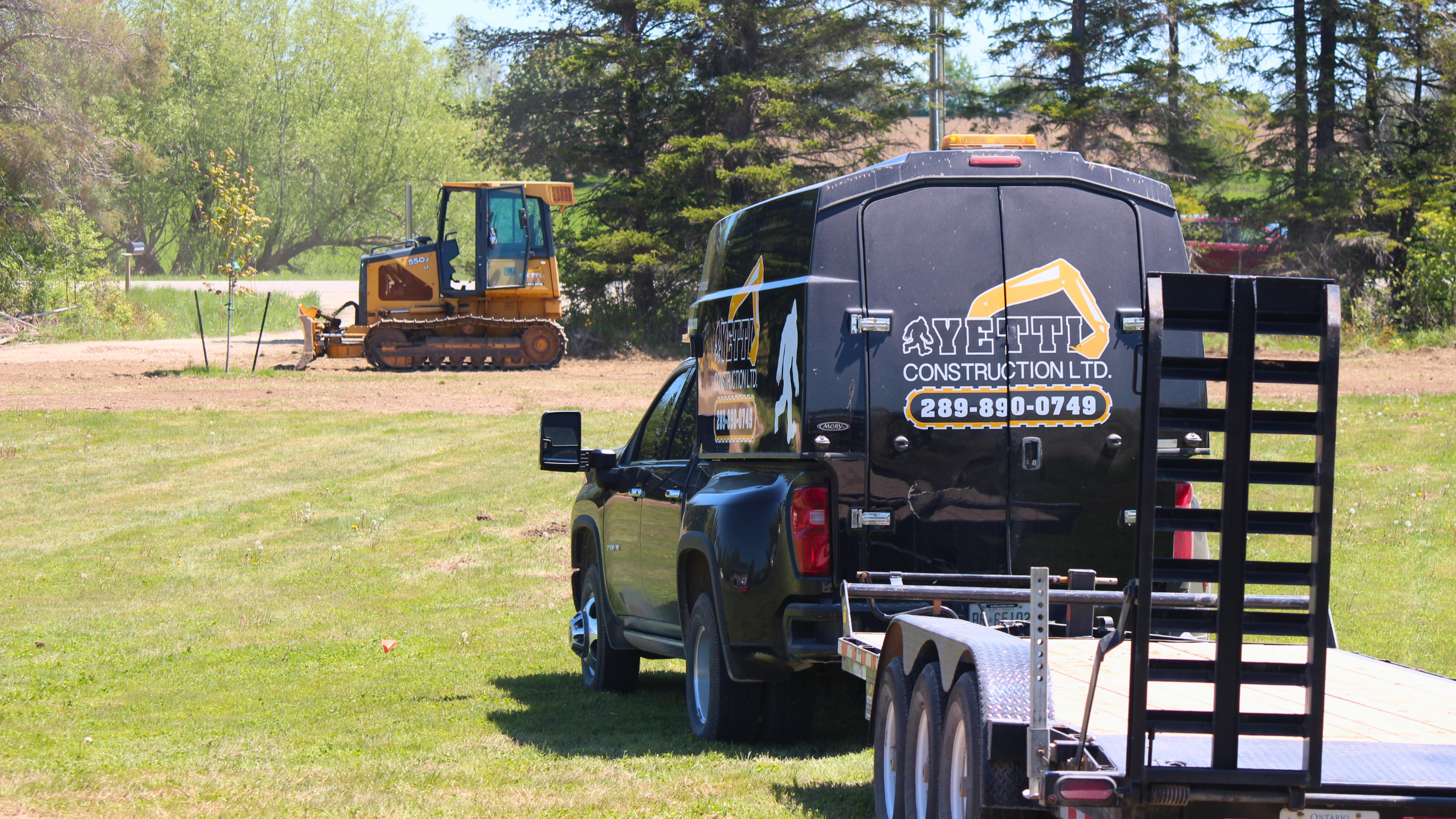 Yetti Construction branded truck and trailer parked near a John Deere dozer on site