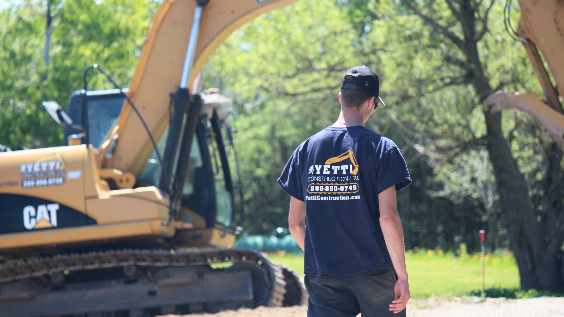 Yetti Construction team member in branded shirt walking toward equipment on site