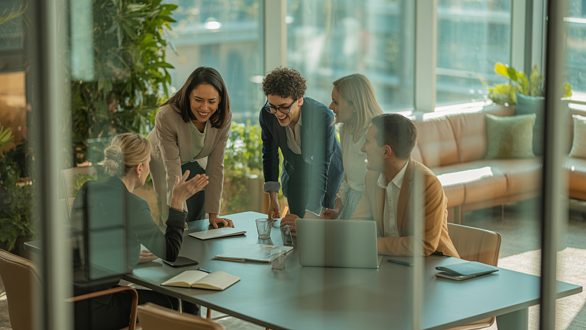 Team collaborating around a table in a glass walled office meeting