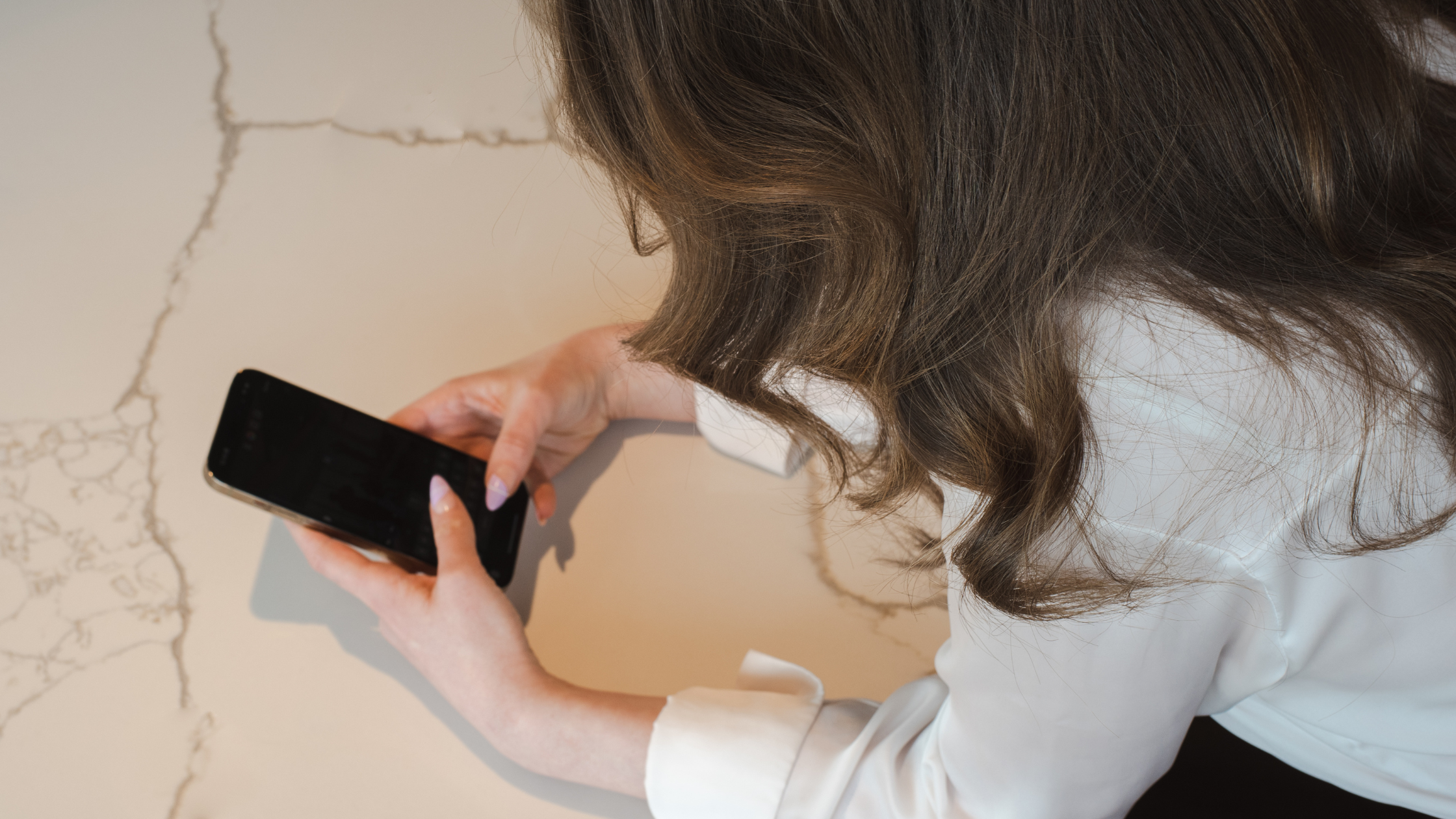 Woman checking her phone against a marble textured wall