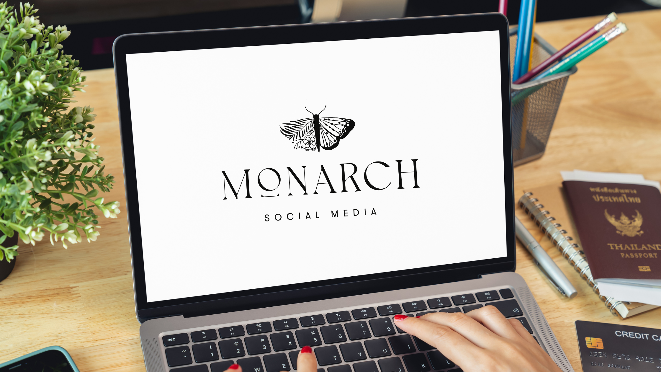 Laptop screen displaying the Monarch Social Media butterfly logo on a desk