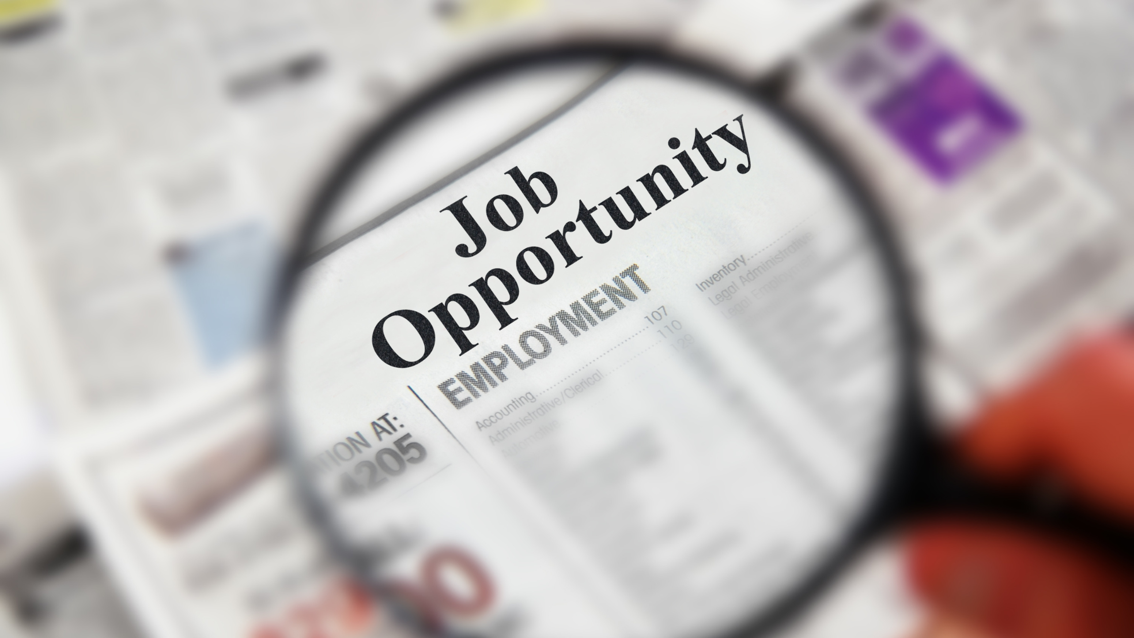 Magnifying glass over a newspaper job opportunity listing, representing a team member finding a social media role through AI search