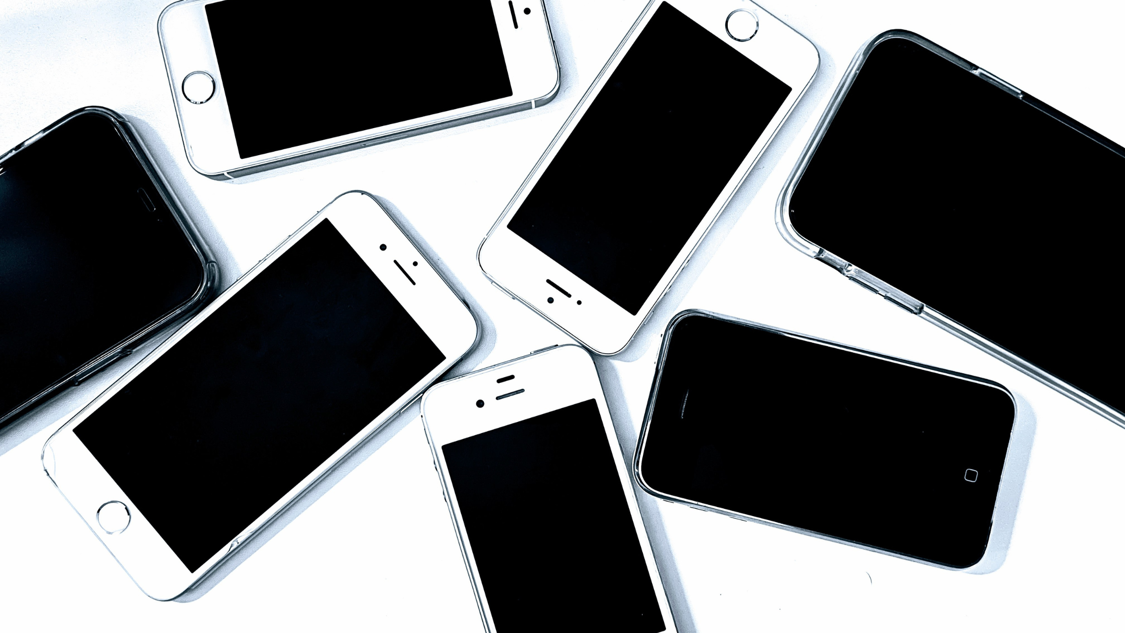 Collection of older and newer smartphones scattered on a white surface, representing how social media strategy has changed over time