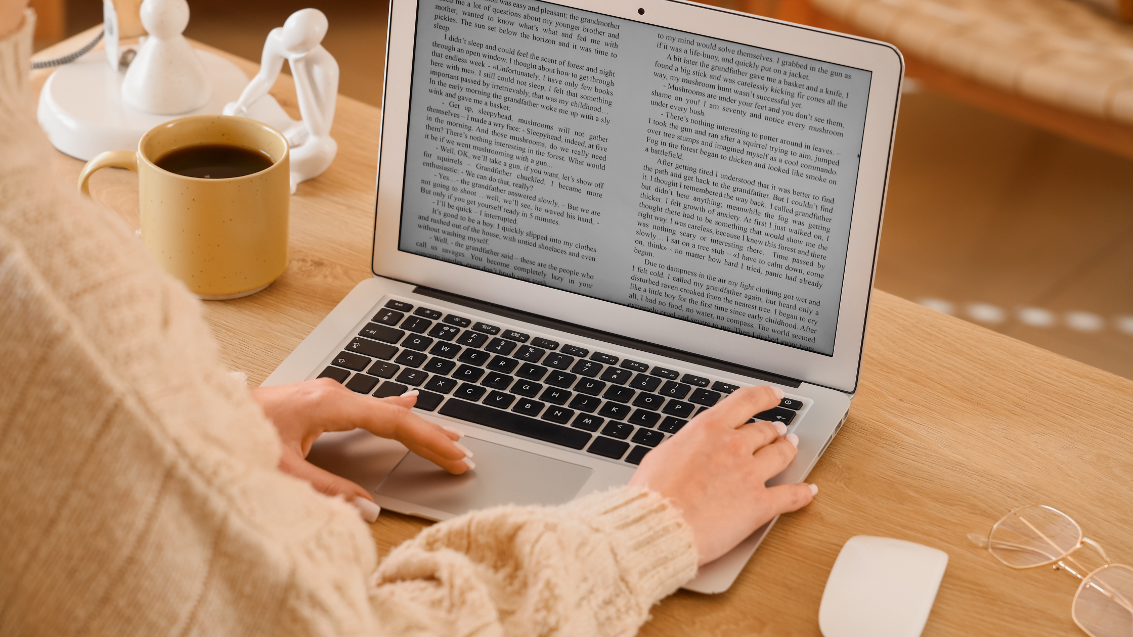 Woman in a cream knit sweater working at a laptop with a coffee mug, planning how to build brand awareness on social media