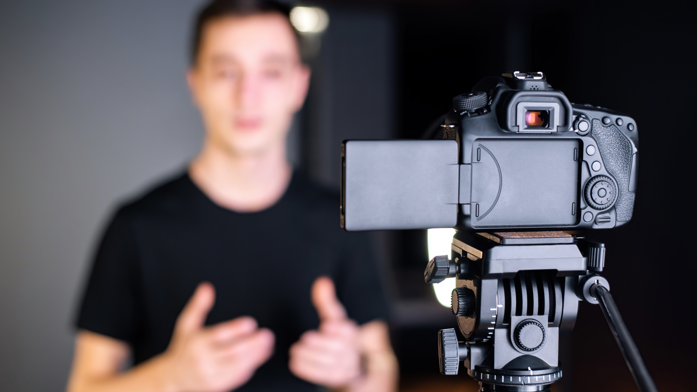 Man in a black t-shirt speaking to a DSLR camera on a tripod, representing influencer marketing and polished creator video production