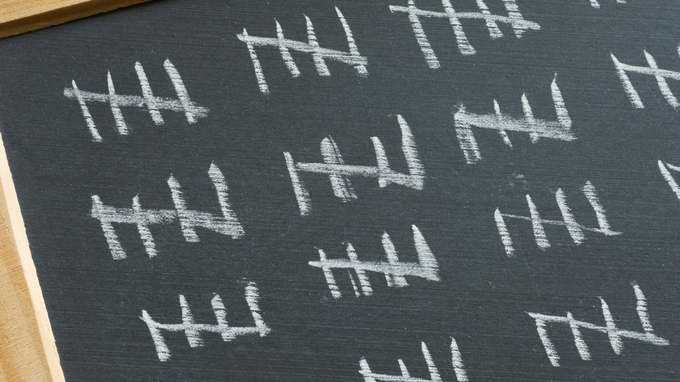 White chalk tally marks counted in groups on a blackboard, representing followers as a vanity metric