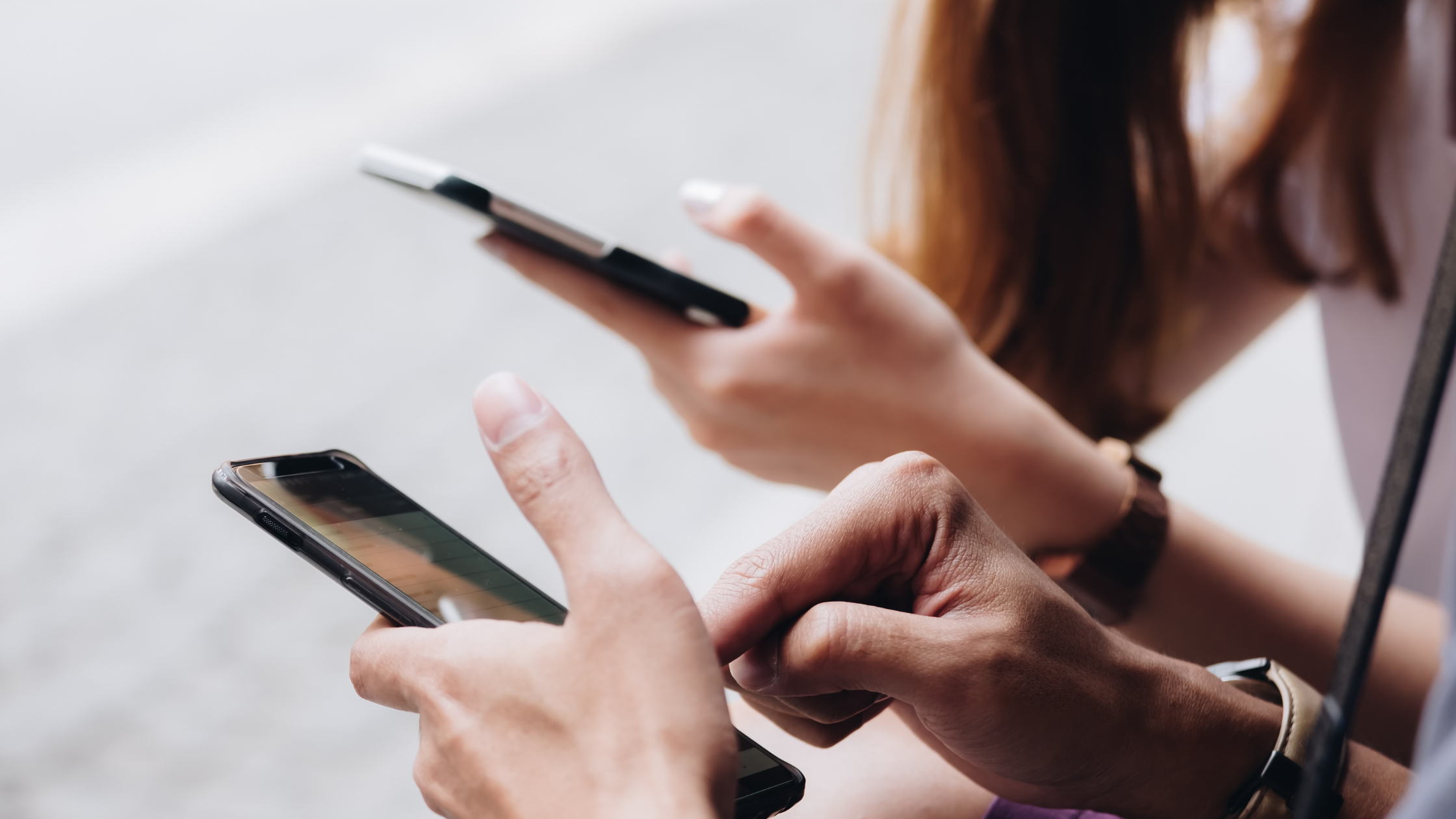 Two people scrolling their smartphones side by side, representing content reaching non-followers through interest-based feeds